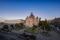 Un grupo de personas caminando por una ciudad con un edificio. en OYO Hostal Mich, en Morelia