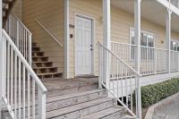 ein Haus mit einer Holztreppe, die zu einer weißen Tür führt in der Unterkunft Beautiful Two Bedroom, Two Bathroom First Floor Condo in Gulf Shores! in Gulf Shores