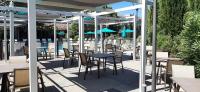 a patio with tables and chairs and blue umbrellas at SOWELL HOTELS Domaine de la Petite Isle in LʼIsle-sur-la-Sorgue