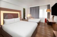a hotel room with two beds and a desk at Novotel London West in London