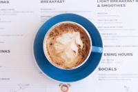 een kop koffie op een tafel met een menukaart bij Parkes International in Parkes