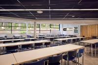 トゥルクにあるHotel Linnasmäkiのテーブルと椅子と窓のある空の教室