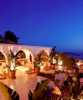 een patio met tafels en stoelen in de nacht bij Hotiday Mykonos Fanari in Mykonos-stad