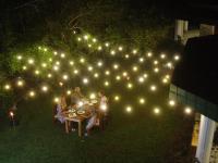 um grupo de pessoas sentadas à mesa sob luzes em Kandahena Mansion em Akuressa