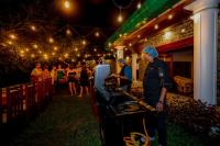 um grupo de pessoas em pé ao redor de uma grelha em uma festa em Kandahena Mansion em Akuressa