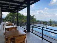 een restaurant met tafels en een balkon met uitzicht bij Tebing View Glamping, Azana Hotels Collection in Tutugan