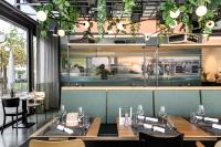 a restaurant with tables and chairs in a room with plants at HOTEL APART - Welcoming l Urban Feel l Design in Rotkreuz