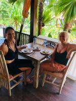 Dos mujeres sentadas en una mesa con comida. en Puri Sari Villas, Restaurant and Bar, en Nusa Lembongan