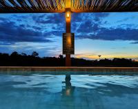 a swimming pool with a sunset in the background at Resort QSB - Um novo padrão de conforto e lazer no coração da cidade in Pirenópolis