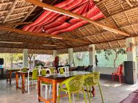 Un restaurante con mesas y sillas bajo techo. en Sundarban Jungle Retreat, en Purbbadulki