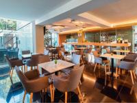 a restaurant with tables and chairs in a room at Hotel Zena Beauty & Shopping Center in Hévíz