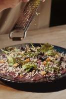 a person is cutting a pizza with a spatula at De Pingerhoeve in Nuth