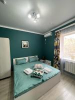 Un dormitorio con una cama con paredes azules y una ventana. en Мини-гостиница Береке, en Aktobe