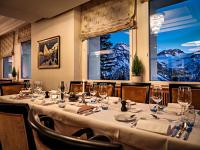 a dining room with a long table with wine glasses at Hotel Prätschli in Arosa