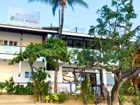 a white hotel with trees in front of it at Suites by Eco Hotels in El Nido