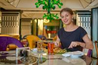 una mujer sentada en una mesa con un plato de comida en Noah Sky Suites, en Kochi