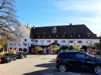 ein schwarzes Auto, das vor einem großen Gebäude geparkt ist in der Unterkunft Ferienwohnung KIostermühle Irsee - Parkplätze, Spielplatz, Biergarten, Badesee, E-Auto Ladepunkt in Irsee