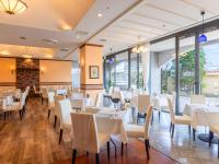 um restaurante com mesas e cadeiras brancas e janelas em Nagasaki International Hotel em Omura