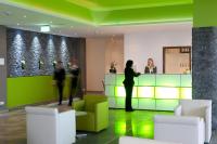 Un hombre de pie en un mostrador en un vestíbulo. en Panorama Hotel Schweinfurt, en Schweinfurt