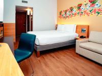 a bedroom with a bed and a chair and a couch at Novotel Cusco in Cusco