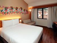 a bedroom with a large white bed and a chair at Novotel Cusco in Cusco