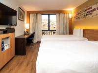 a hotel room with two beds and a desk and a television at Novotel Cusco in Cusco