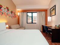 a hotel room with a bed and a desk and a window at Novotel Cusco in Cusco