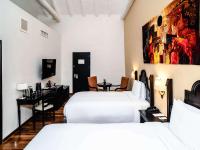 a hotel room with two beds and a desk at Novotel Cusco in Cusco