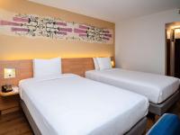 two beds in a hotel room with white sheets at Novotel Cusco in Cusco