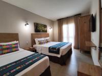 a hotel room with two beds and a window at Resort QSB - Um novo padrão de conforto e lazer no coração da cidade in Pirenópolis