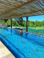 a woman is standing in a swimming pool at Resort QSB - Um novo padrão de conforto e lazer no coração da cidade in Pirenópolis