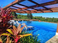 a swimming pool with chairs and a blue swimming pool at Resort QSB - Um novo padrão de conforto e lazer no coração da cidade in Pirenópolis