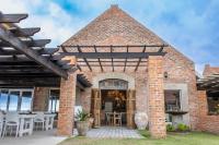 a brick building with an entrance with tables and chairs at Seeplaas Guesthouse in Groot Brak Rivier