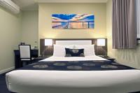 a bedroom with a large white bed and a desk at Park Squire Motor Inn &amp; Serviced Apartments in Melbourne