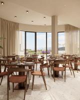 un ristorante con tavoli e sedie in legno e finestre di Hotel Kali a Kali