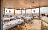 a restaurant with tables and chairs and views of the ocean at Zafora Cave Suites Hotel Cappadocia in Uchisar