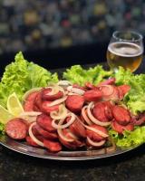 a plate of hot dogs and lettuce with a glass of beer at Pousada Fazenda coronel in Camanducaia