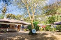 a house with a tree in front of it at The Farmhouse Inn in Nanyuki