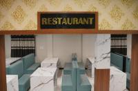 Una sala de espera con sillas verdes y un cartel de restaurante. en Hotel Shree Radhe Krishna, en Ujjain