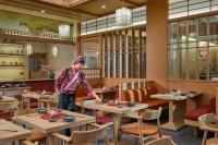 Una mujer de pie en un comedor con mesas. en Sakurakyo Hotel & Spa Phu Quoc, en Phu Quoc