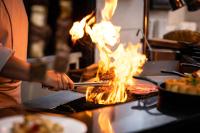 ソウルにあるKensington Hotel Yeouidoの人が炎のついたグリルで食べ物を調理している