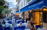 a group of people sitting at tables outside a restaurant at Hotel Le Suquet Cannes in Cannes