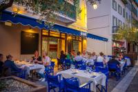 a group of people sitting at tables outside a restaurant at Hotel Le Suquet Cannes in Cannes