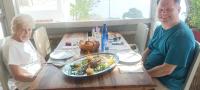a man and woman sitting at a table with a plate of food at Poseidon Apartments and Villas by the Sea in Sounio