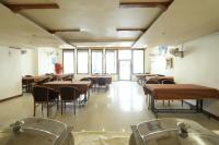 Un comedor con mesas y sillas y ventanas. en Hotel Aagam Executive, en Aurangabad