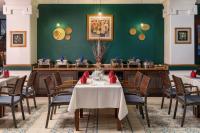 a dining room with tables and chairs and a green wall at Hoi An Odyssey Hotel & Spa in Hoi An