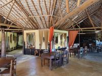 una sala da pranzo con soffitti e tavoli in legno e sedie di Hôtel de la Plage ad Ambolomailaka