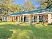 ein großes Haus mit Glasfenstern und einem Garten in der Unterkunft Elsamere Lodge Naivasha in Naivasha