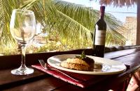 パジェにあるSand and Sunset JGM Hotel, Pajeのテーブルの上に一皿とワイン1杯