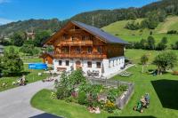 a large wooden house with people sitting in the grass at Hinkerhof in Schladming